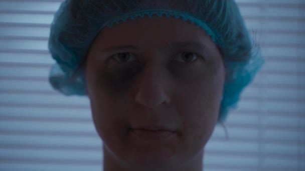 Een bange, getraumatiseerde vrouw met verwondingen aan haar tanden en gezicht kijkt naar de camera in haar ziekenhuis kleren in de kliniek - Video
