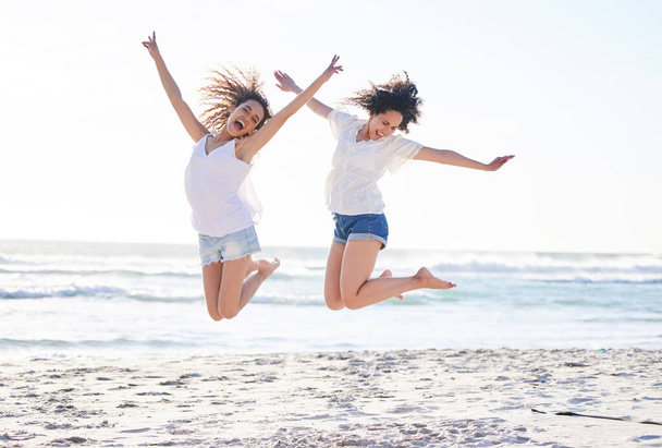 Celebrate your friendship everyday. Shot of two young women jumping for joy at the beach. - Фото, изображение