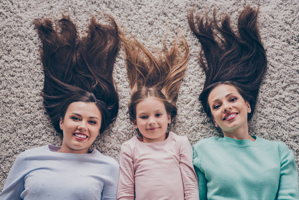 Top above high angle view portrait of attractive funny cheerful family girlfriends resting having fun lying on carpet at home indoors - Foto, imagen