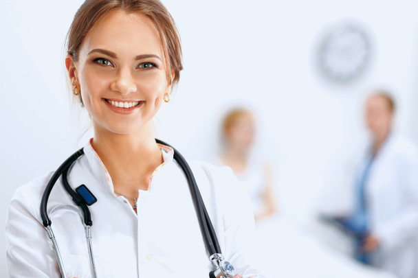 Woman doctor smiling and looking to the camera while a medical team is working. - 写真・画像