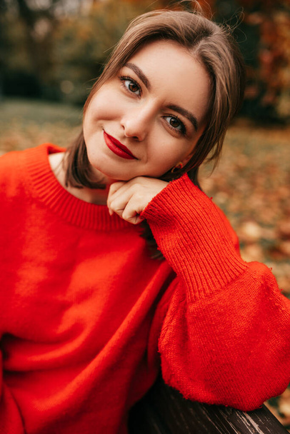 Függőleges portré gyönyörű fiatal nő, támaszkodó kéz, ül padon őszi parkban. Lazító, szemlélődő természet - Fotó, kép