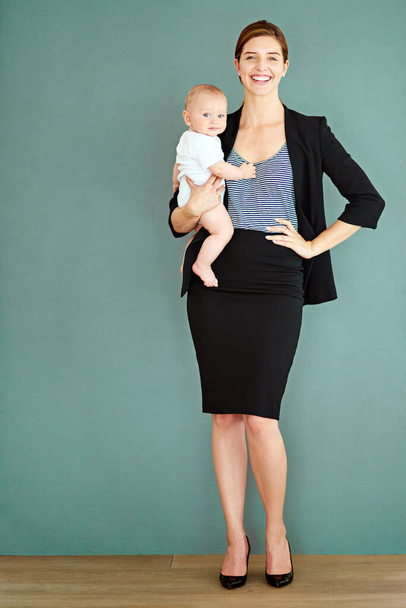 Ik ben een trotse werkende moeder van een mooie kleine jongen. Studio shot van een succesvolle jonge zakenvrouw dragen haar schattige baby jongen. - Foto, afbeelding