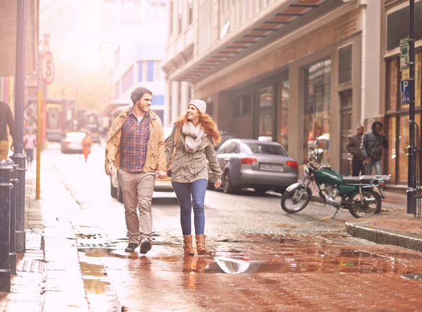 Enjoying a winter walk together. Shot of a happy young couple walking through an urban area together. - Foto, imagen