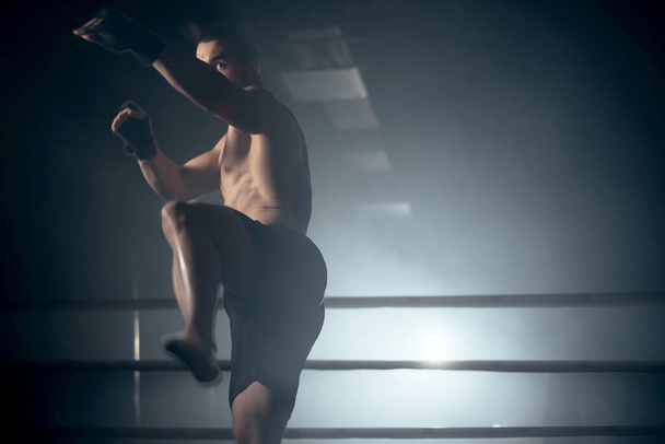 Musculaire MMA-vechter oefent kick, vechtclub concept. - Foto, afbeelding