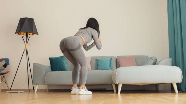 Athlétique femme sport séance d'entraînement à la maison, squats. Entraînement à domicile. - Photo, image