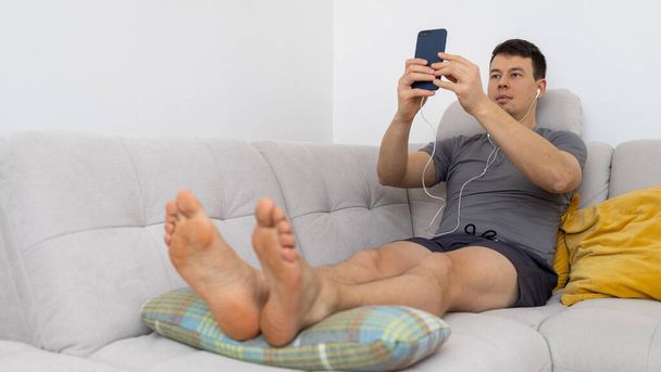 jonge man in koptelefoon kijken op mobiele telefoon - Foto, afbeelding