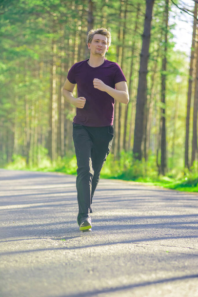 Man jogging in city partk at beautiful summer day. Sport fitness model caucasian ethnicity training outdoor. - Zdjęcie, obraz