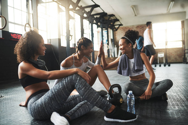 Best friends motivate you to be better. Shot of young women giving each other a high five while taking a break at the gym. - Photo, Image