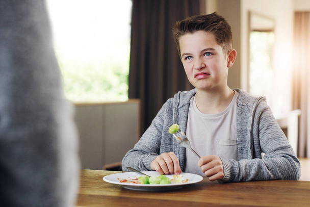 Id rather go to bed hungry. Shot of a young boy refusing to eat his brussels sprouts at home. - Foto, imagen