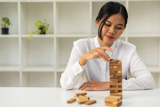 Risks and strategies, planning, gambling by hand. Placing wooden blocks on the tower Girl Builds a Pyramid of Sticks - Fun in the Office Girl Planning the Future she believes in success - Foto, Bild