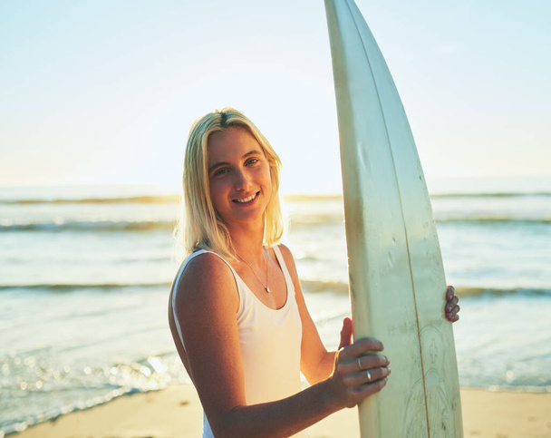 O oceano é um sonho de surfistas. Retrato recortado de uma jovem atraente de pé em um maiô segurando uma prancha de surf na praia. - Foto, Imagem