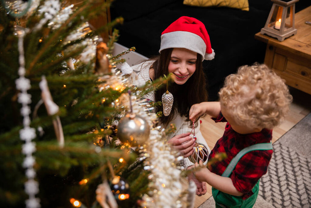 A sister helps her young brother hang ornaments for the Christmas tree. - Foto, Imagem