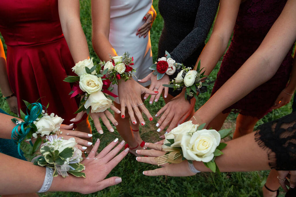A circle of wrist corsages before a school prom dance. Beautiful group of girls wearing traditional flowers at the homecoming dance - Photo, Image