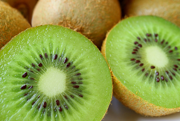 Close-up Twee helften van verse rijpe Kiwi Fruit met hele Fruit in de achtergrond - Foto, afbeelding