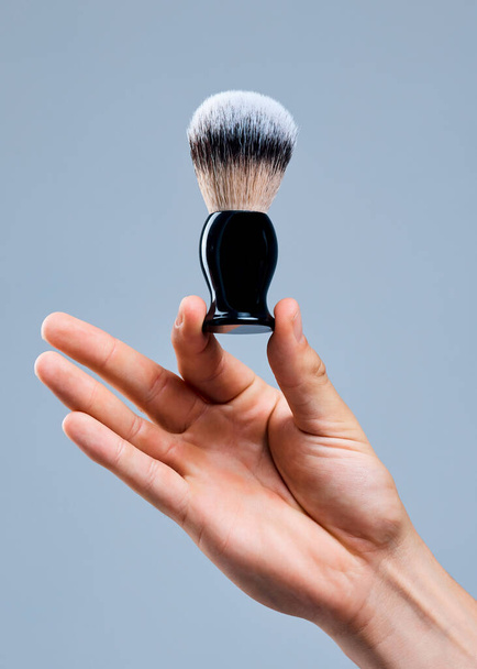 Even application. Shot of an unrecognizable man holding a brush against a grey background. - Photo, Image