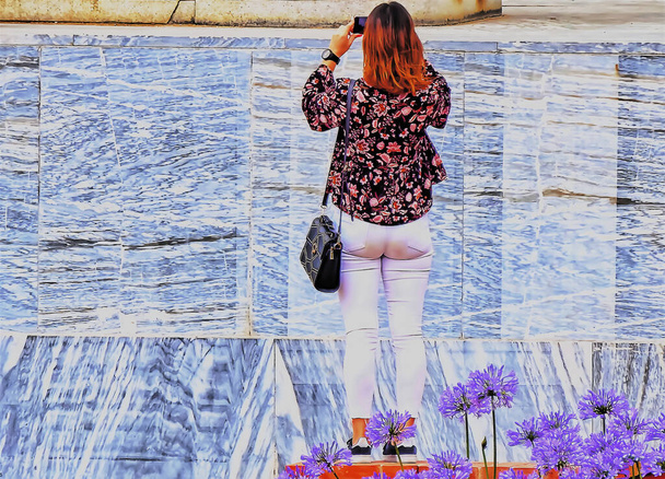 Το πίσω μέρος μιας γυναίκας με κόκκινα μαλλιά τραβώντας φωτογραφίες. - Φωτογραφία, εικόνα