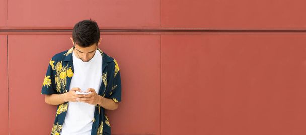 jonge man met mobiele telefoon en tropisch shirt - Foto, afbeelding