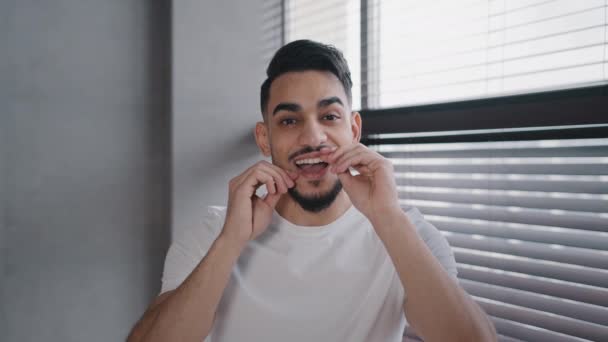 肖像画ミレニアルハンサムなひげを生やしたアラブインディアン男性男で白いシャツブラッシング歯を使用して歯科フロス朝衛生儀式経口クリーニングおもちゃで自宅でバスルームヘルスケア歯科医師の概念 - 映像、動画