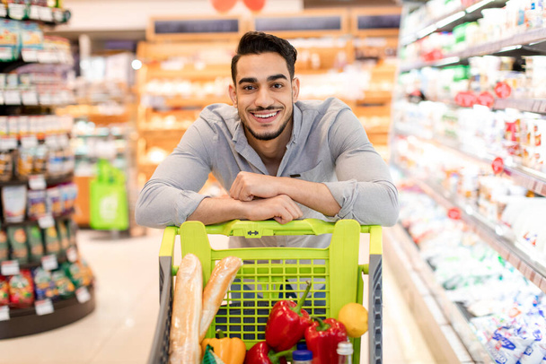 Arabic Guy Posing With Shop Cart Shopping In Modern Supermarket - 写真・画像