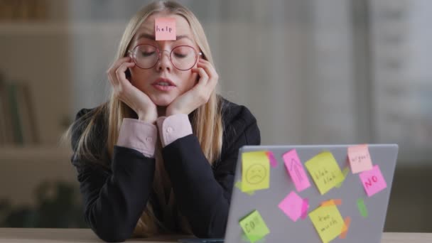 Unavený vyčerpaný obchod žena dívka zaměstnanec manažer sedí v kanceláři stůl s notebookem lepicí poznámky tyčinky s mnoha úkoly nápis pomoc na čele cítí smutný nuda přepracované multitasking - Záběry, video