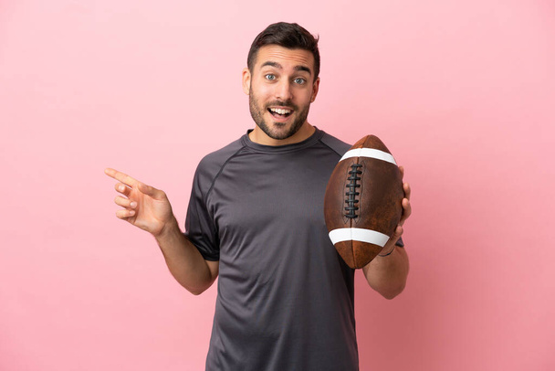 Young caucasian man playing rugby isolated on pink background pointing finger to the side - Photo, Image