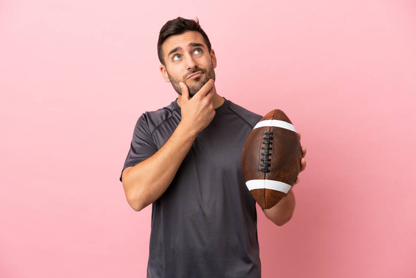 Young caucasian man playing rugby isolated on pink background having doubts - Photo, Image