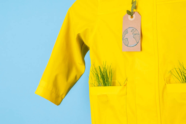 Recyklace deště. Použité svrchní oblečení. Ekologický a udržitelný životní styl. modelovat žlutý plášť na modrém pozadí. Kvalitní fotografie - Fotografie, Obrázek