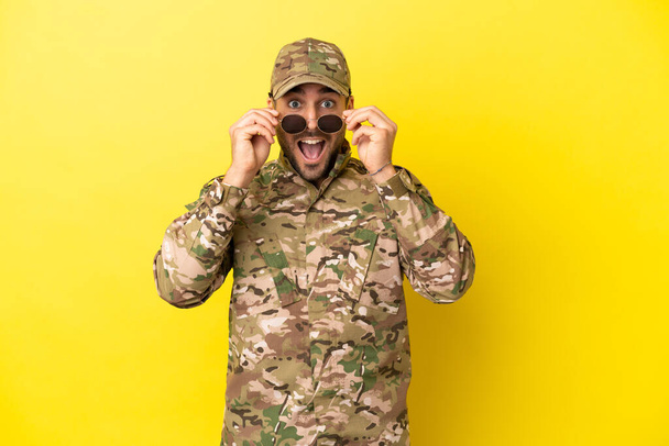 Wojskowy człowiek odizolowany na żółtym tle z okularami i zaskoczony - Zdjęcie, obraz
