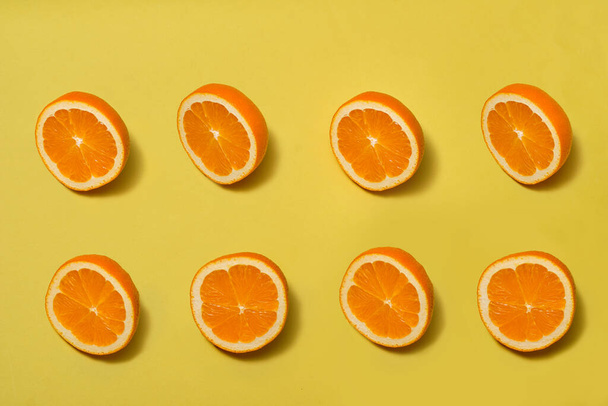 Orange top view with halves ripe orange on yellow background - Фото, изображение