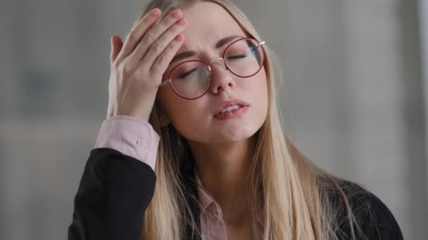 Tired exhausted ill sick business woman girl holding head headache fever feels unwell ache pain suffers from fever fatigue takes off glasses massages forehead health problems pressure stress trouble - Footage, Video