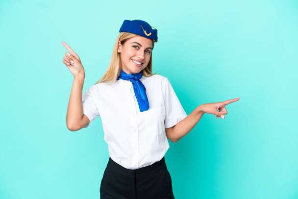 Stewardessa samolotu urugwajska kobieta odizolowana na niebieskim tle wskazując palcem na boki i szczęśliwy - Zdjęcie, obraz