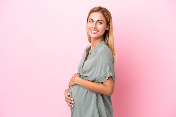 Young Uruguayan woman isolated on blue background pregnant and happy - Foto, immagini