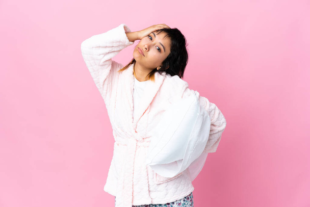 Jonge Uruguayaanse vrouw in pyjama over geïsoleerde roze achtergrond - Foto, afbeelding
