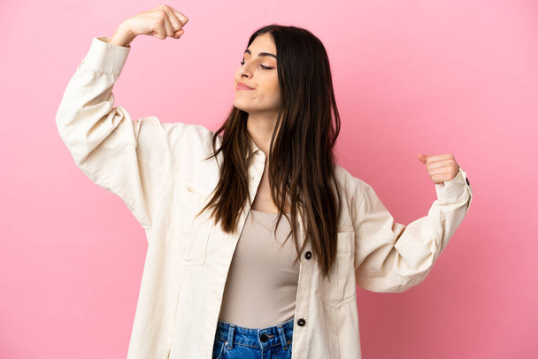 Young caucasian woman isolated on pink background doing strong gesture - Photo, Image