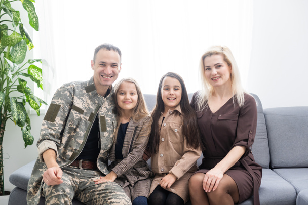 Солдат в камуфляжі і його сім'я сидить вдома
 - Фото, зображення