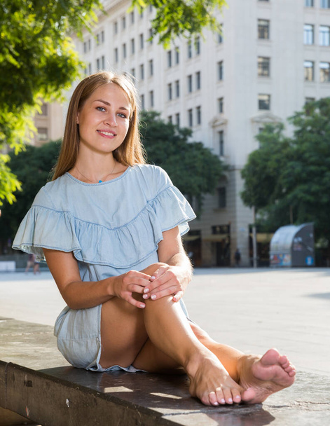 Girl sitting on parapet in center of city - Фото, изображение