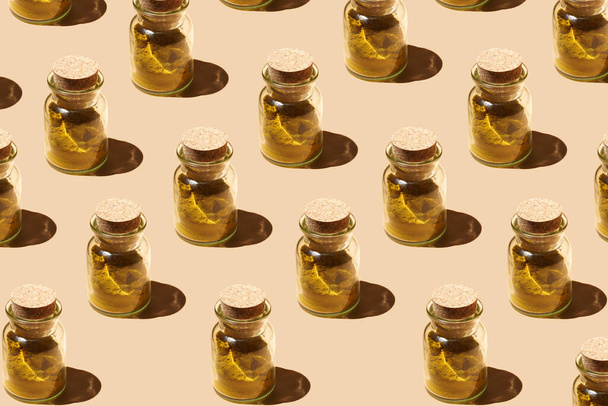 A hard light pattern of a glass jar with cork lids containing curry spice on pastel yellow seamless surface in hard light - Foto, immagini