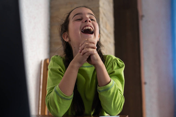 маленькая девочка смеется с тарелками во рту. - Фото, изображение