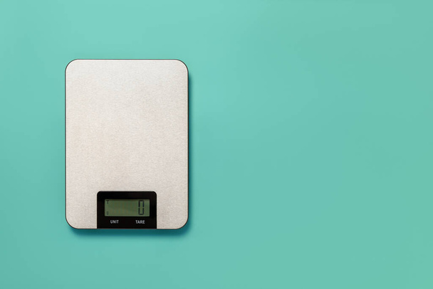 Digital kitchen scales against turquoise background. Electronic scales for food weight measurement. Design element for dieting and cooking concepts. Household measuring device. Copy space. Top view. - Foto, Bild
