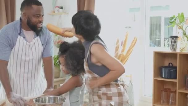 Famiglia afroamericana indossa grembiule trebbia farina per cucinare e ballare e cantare insieme in cucina a casa, genitore e bambino preparare cibo e canto con divertimento e giocoso. - Filmati, video