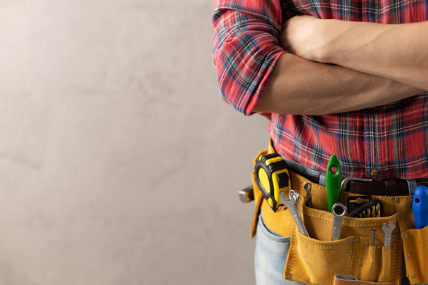 Worker man with tool belt near concrete or cement wall. Male hand and tools for house room renovation. Home renovation concept - Valokuva, kuva