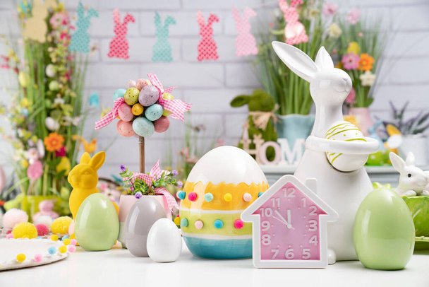 Easter time. Easter decorations on the white background. Easter bunny, easter eggs in basket. Bouquets of spring flowers.  - Photo, Image