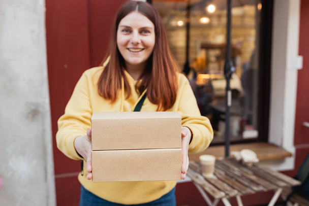 Щаслива посмішка Жінка Руків'я, що тримає два продуктових контейнери біля ресторану. Швидка упаковка еко з великим сніданком. Середовище переробки еко. - Фото, зображення