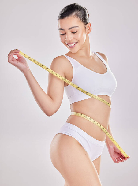 If youre feeling good on the inside, youre looking great on the outside. Studio shot of a fit young woman holding a measuring tape around her waist. - Foto, immagini