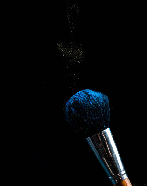 make-up brush with powder of different colors on a dark background like space dust - Fotó, kép