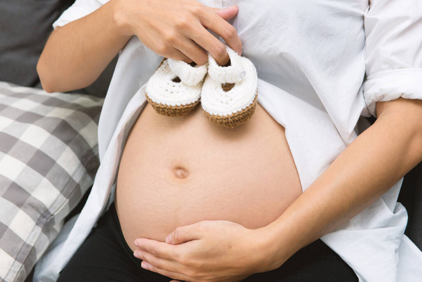Petites chaussures pour bébé dans le ventre de la femme enceinte
. - Photo, image
