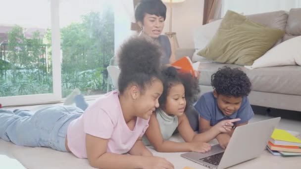 Anne ve çocuklarla mutlu bir Afrikalı aile dizüstü bilgisayarı kullanarak online video izleyerek evdeki oturma odasında öğrenim görüyor, anne çocuğuna öğretiyor, eğitim kavramını anlatıyor.. - Video, Çekim