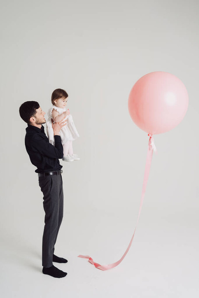 Πατέρας κόρη στιγμή βλέποντας ένα ροζ μπαλόνι σε λευκό φόντο - Φωτογραφία, εικόνα