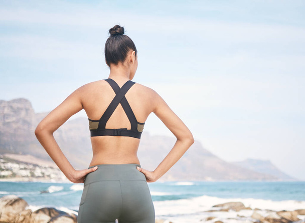 Как вы можете не быть мотивированы этим взглядом. Фотография неузнаваемой атлетичной молодой женщины, стоящей с руками на бедрах во время тренировки на пляже. - Фото, изображение