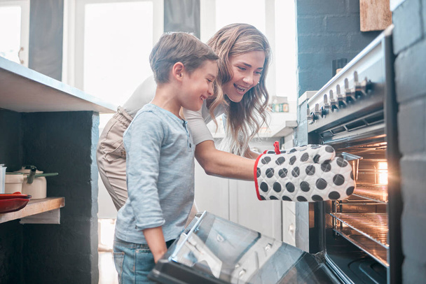 Koken en bakken is zowel fysieke als mentale therapie. Schot van een kleine jongen en zijn moeder zittend voor de oven. - Foto, afbeelding